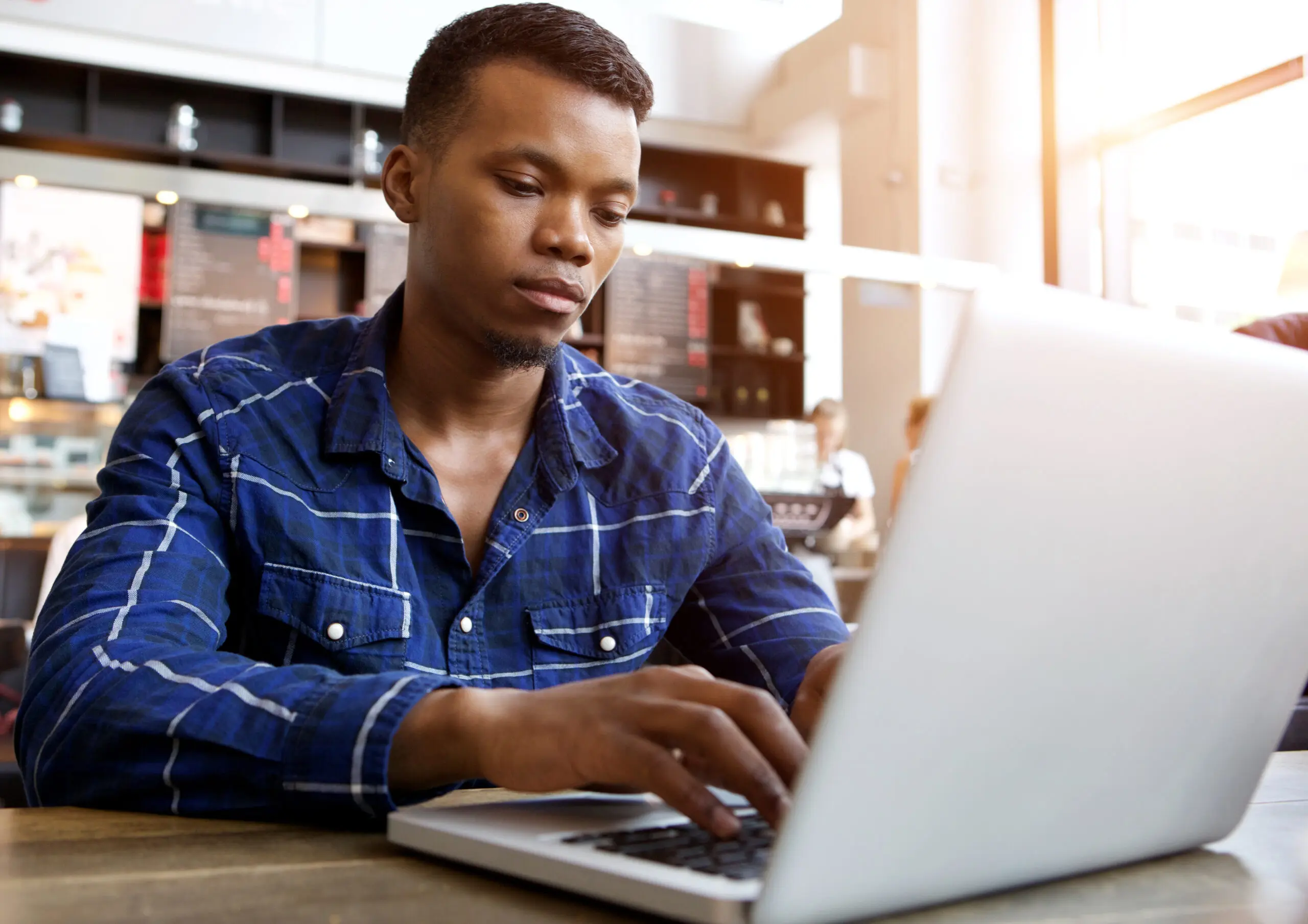 Serious Young Man Sitting In Cafe Using Laptop